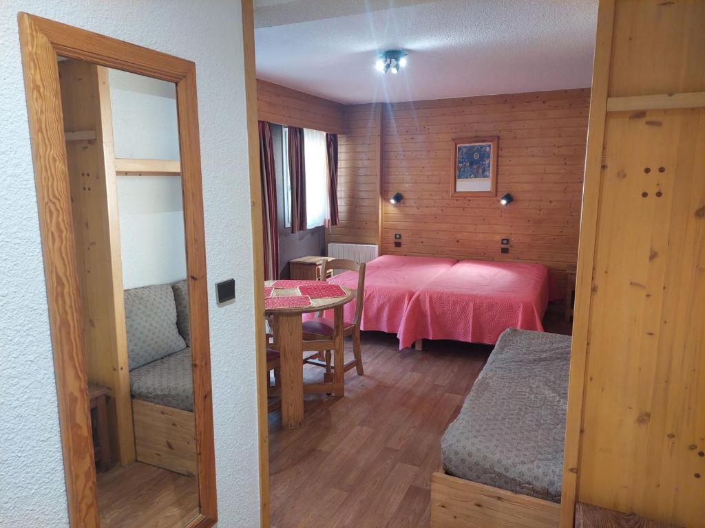 - une chambre avec un lit rose et une table dans l'établissement Studio cosy au cœur de Brides-les-Bains, balcon, wifi, parking, animaux admis - FR-1-512-282, à Brides-les-Bains
