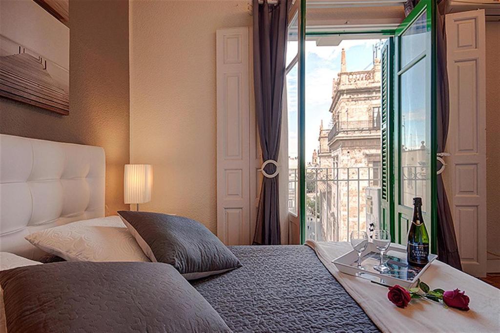 um quarto com uma cama e uma janela com uma garrafa de vinho em Beds & Breaks Gade em Valência
