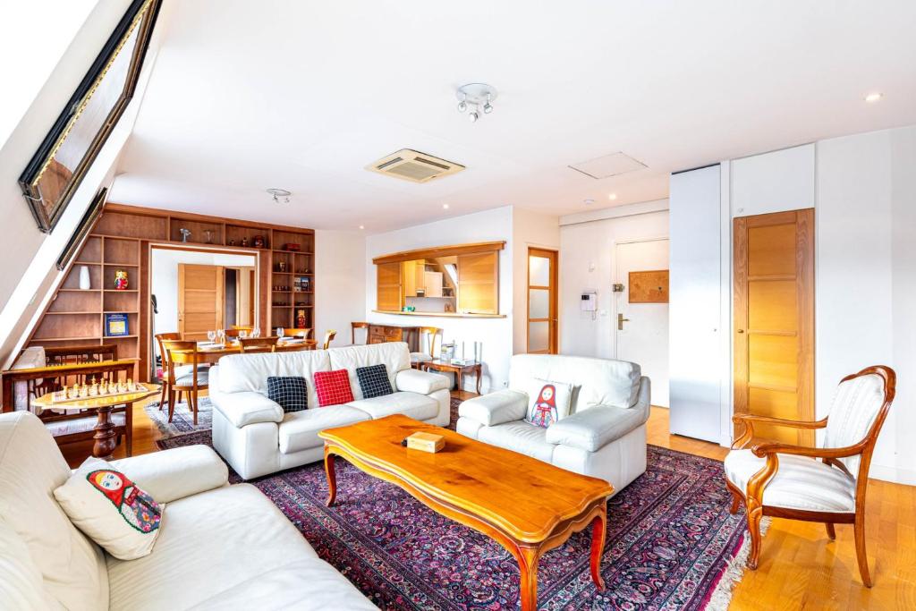 un salon avec des meubles blancs et une table dans l'établissement GuestReady - Spacious Comfort in the 8th, à Paris