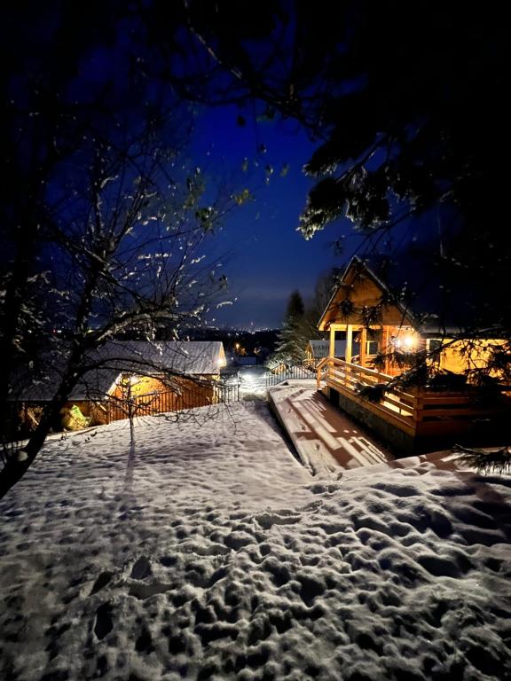 una calle cubierta de nieve por la noche con una casa en Domki Habzówka, en Ostre