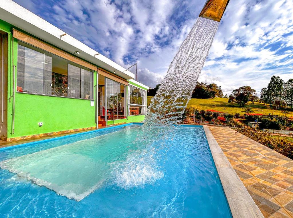 a swimming pool with a fountain in front of a house at Refúgio nas montanhas em Extrema com cachoeira in Extrema