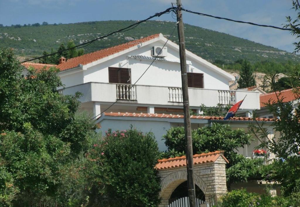 a white house with a balcony on a hill at Apartment Tina in Obrovac