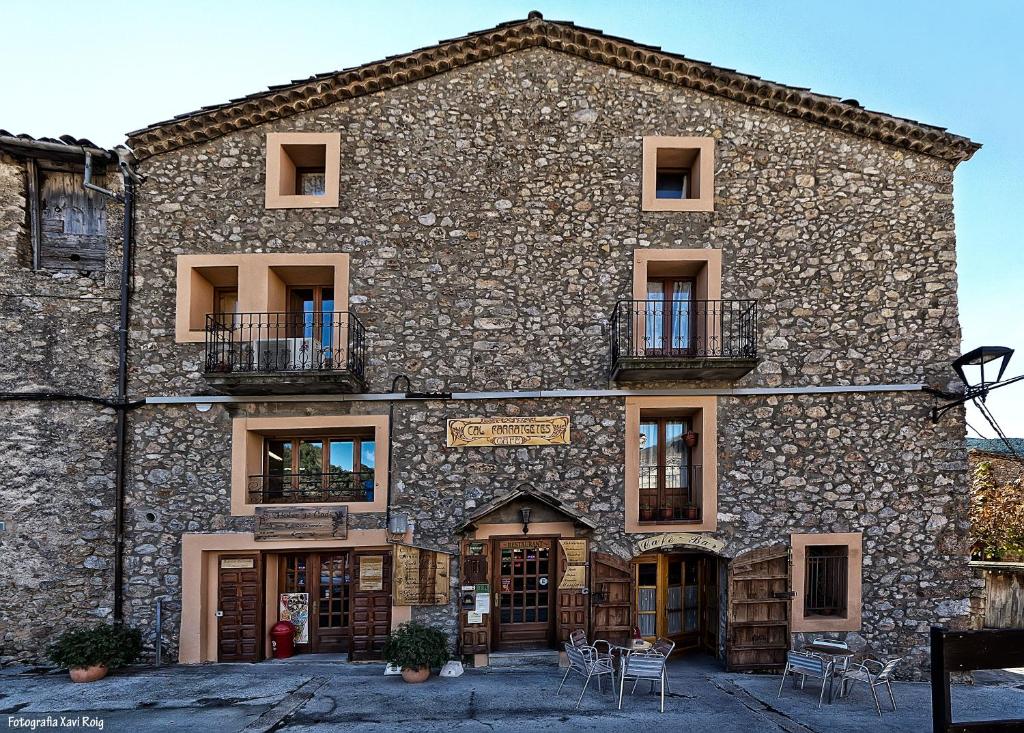 a stone building with tables and chairs in front of it at Casa Rural Cal Farragetes in Tuixen