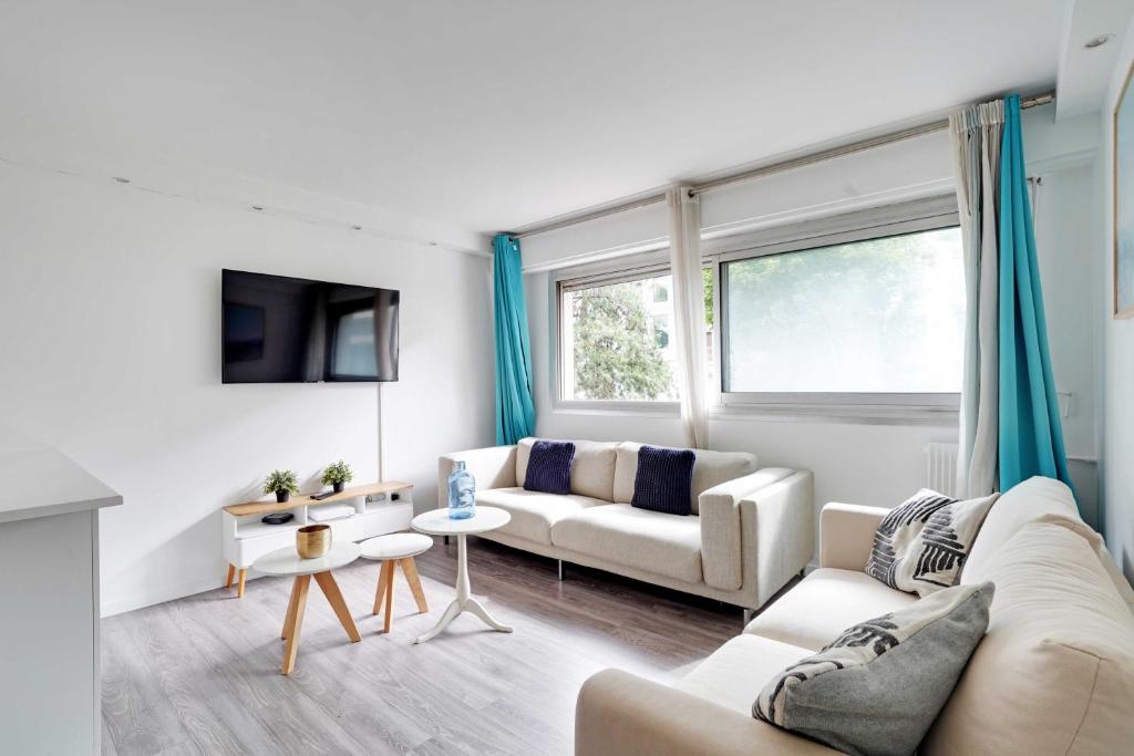 Elle comprend un salon doté d'un mobilier blanc et de rideaux bleus. dans l'établissement Magnificent apartment - 2BR-6P - Levallois-Perret, à Levallois-Perret