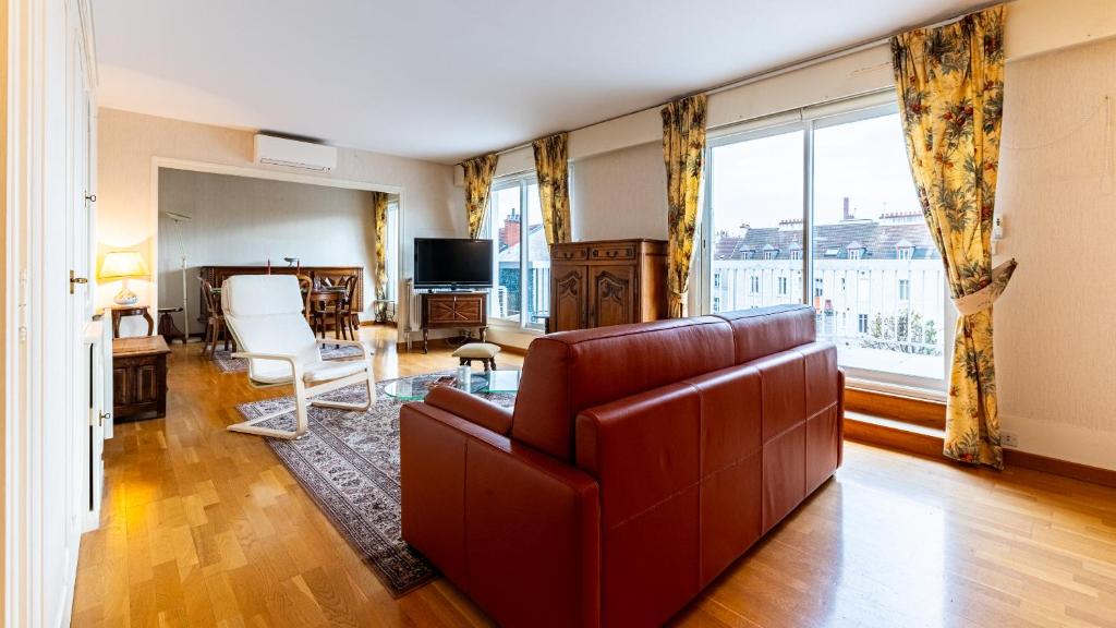 un salon avec un canapé et une grande fenêtre dans l'établissement L'Edito - Centre Ville - Gare - Balcon - 6prs, à Dijon