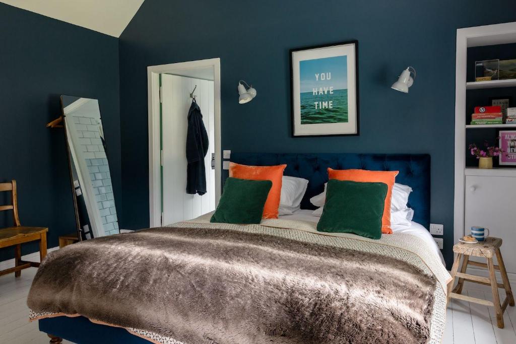 a bedroom with a large bed with orange and green pillows at The Bothy in Banchory