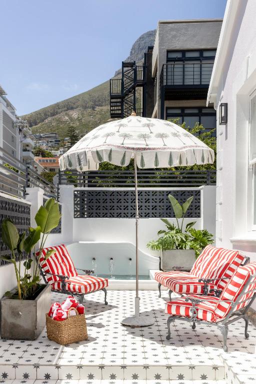 two chairs and an umbrella on a patio at Petit Pineapple House in Cape Town