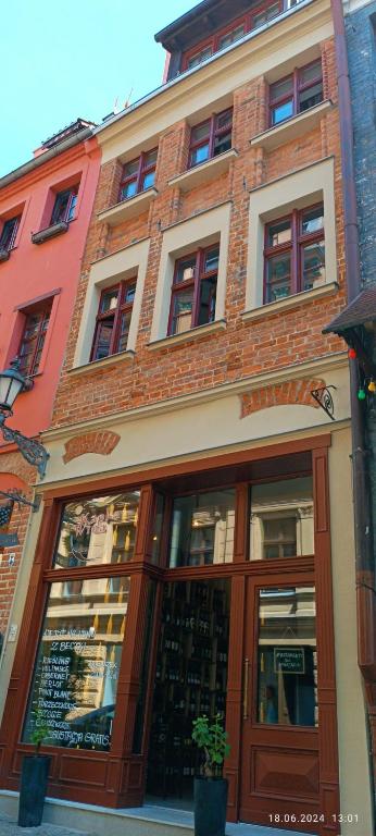 Hotel Kapka wina, a red brick building with a store front at Kapka wina in Toruń