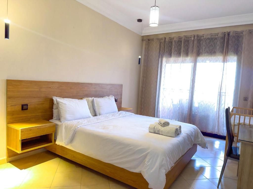 ein Schlafzimmer mit großem Bett und Fenster in der Unterkunft Top localisation, neuf, Piscine et une vue balcon in Marrakesch