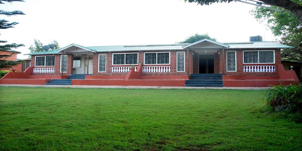 a house with a green lawn in front of it at The Byke Sai Cottage Mahabaleshwar in Mahabaleshwar