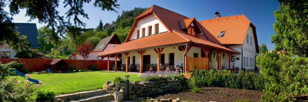 a house with an orange roof and a yard at Penzion Rozmarýn in Vsetín