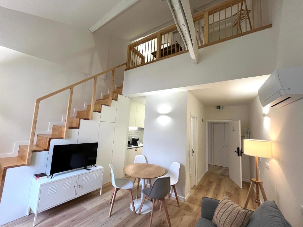 a living room with a table and a tv and stairs at Casas de Alpedide in Coimbra