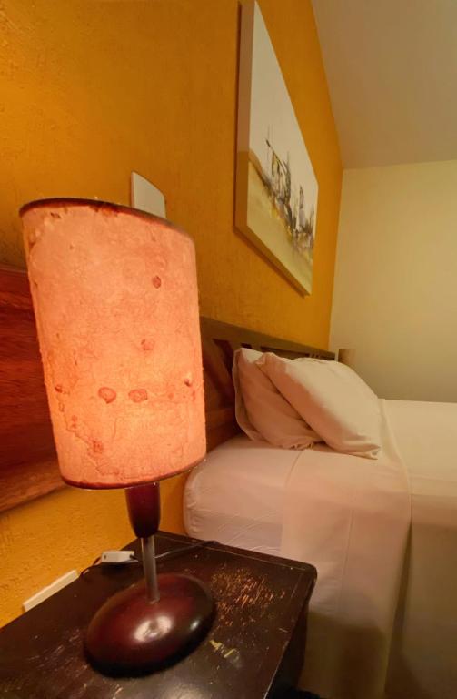 a bedroom with a bed and a table with a lamp at Villa Zen Pirenópolis Conforto e Bem-Estar in Pirenópolis