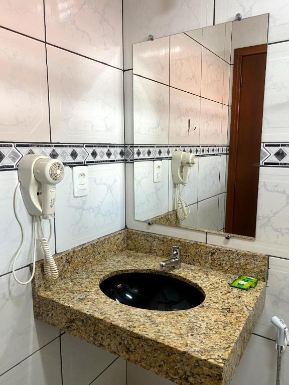 a bathroom with a sink with a phone and a mirror at Villa Zen Pirenópolis Conforto e Bem-Estar in Pirenópolis