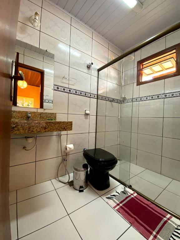 a bathroom with a black toilet and a mirror at Villa Zen Pirenópolis Conforto e Bem-Estar in Pirenópolis