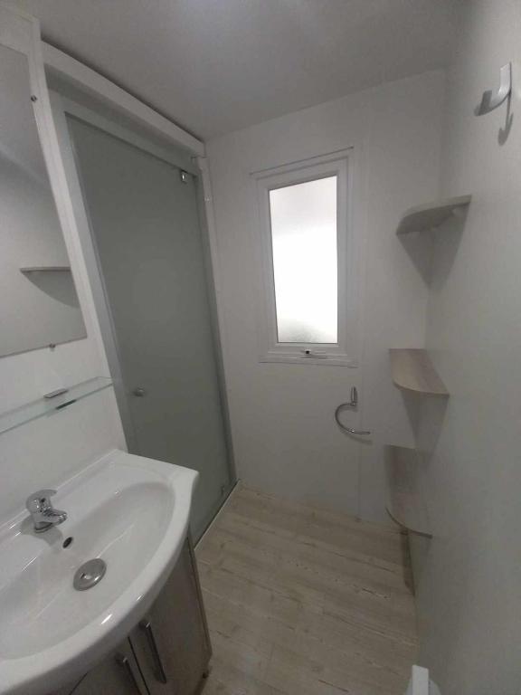 une salle de bain blanche avec un lavabo et une fenêtre dans l'établissement MH 515 AMIRA TOUT CONFORT 3ch et 2sdb dans camping 4étoiles avec parc aquatique, à Saint-Julien-en-Born