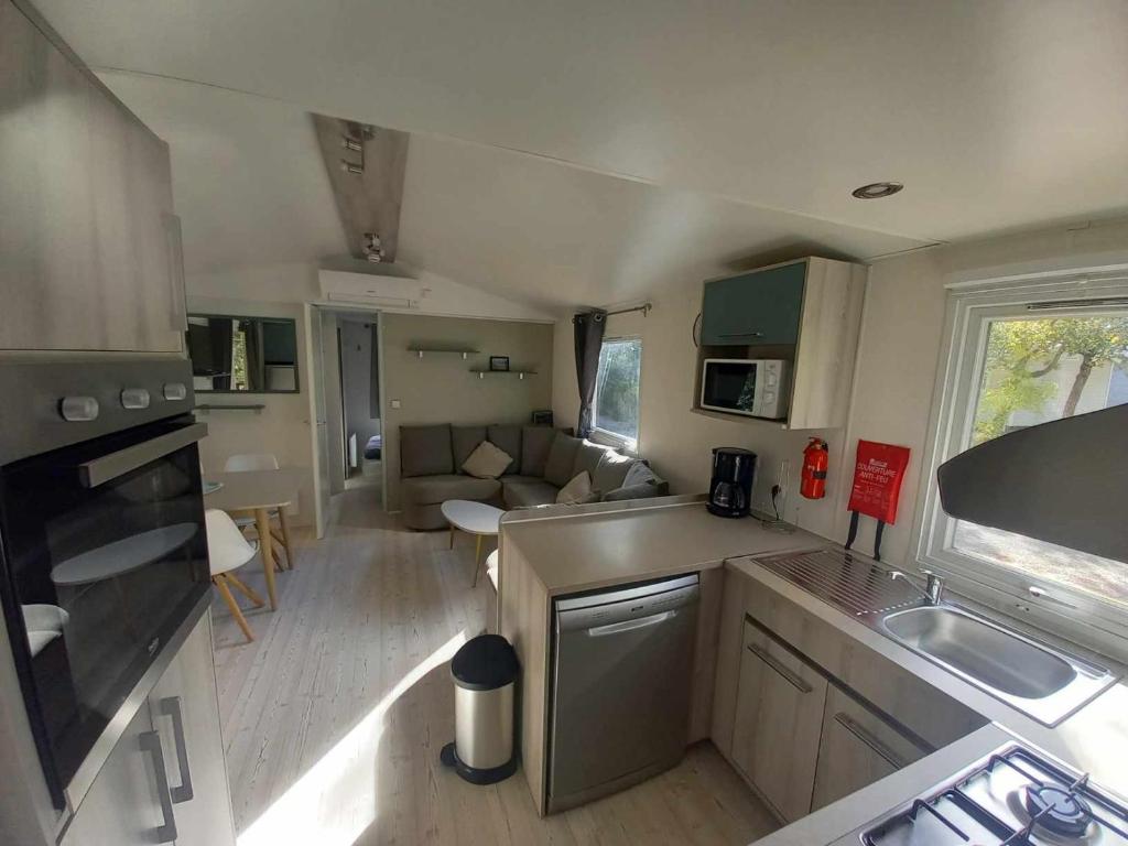 Cette caravane comprend une petite cuisine et un salon. dans l'établissement MH 515 AMIRA TOUT CONFORT 3ch et 2sdb dans camping 4étoiles avec parc aquatique, à Saint-Julien-en-Born