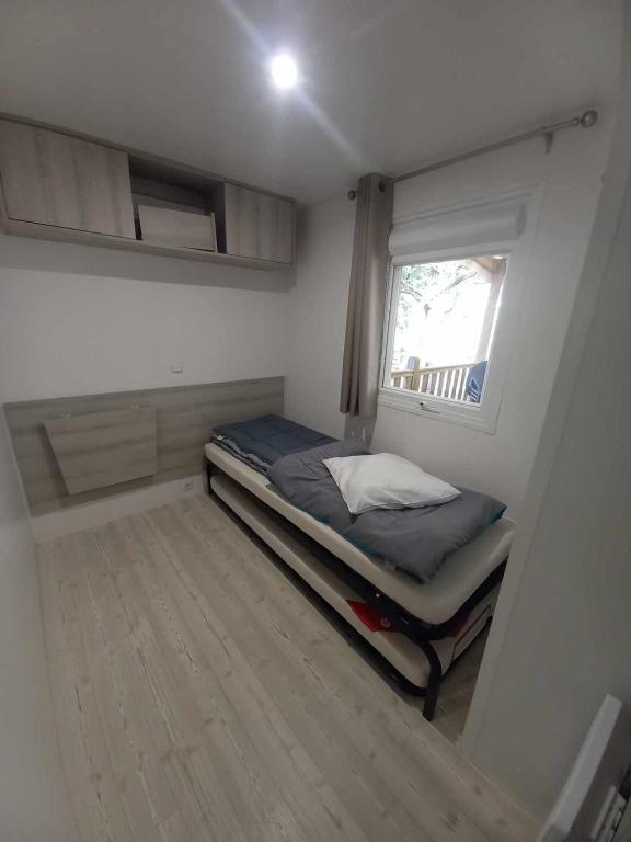 une petite chambre avec un lit et une fenêtre dans l'établissement MH 515 AMIRA TOUT CONFORT 3ch et 2sdb dans camping 4étoiles avec parc aquatique, à Saint-Julien-en-Born