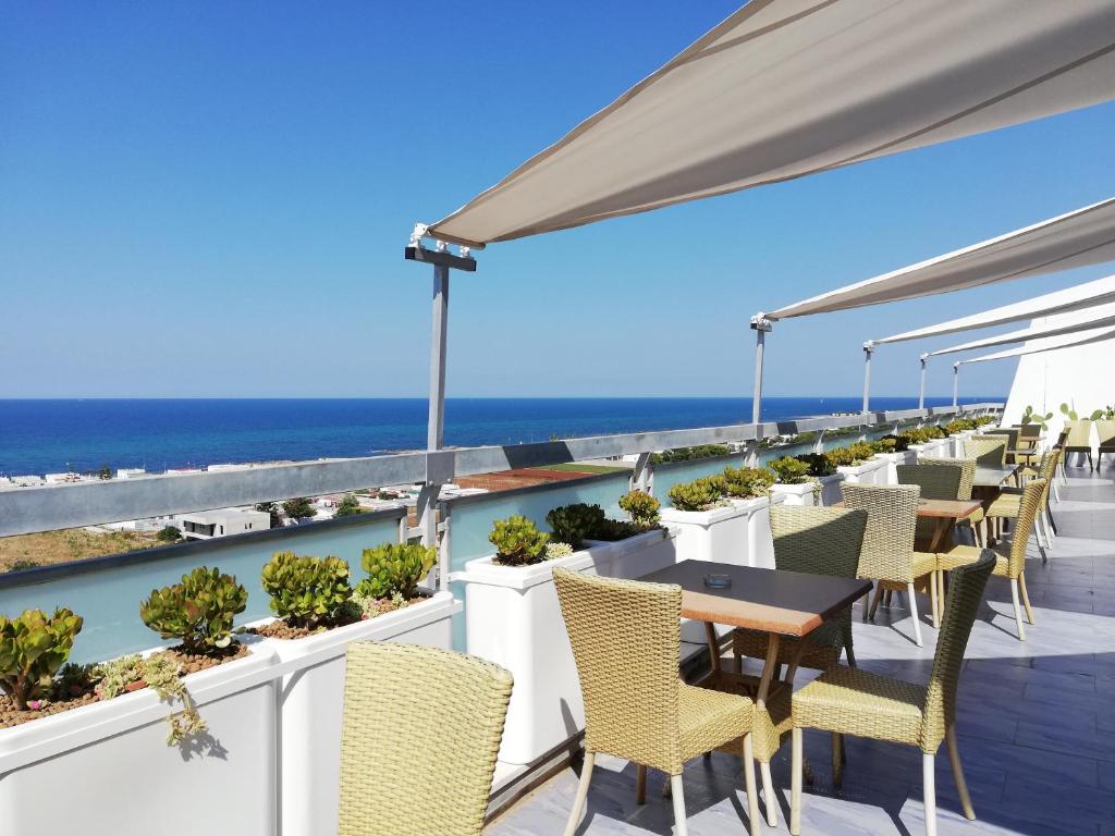 a patio with tables and chairs and the ocean at Barion Hotel & Congressi in Bari