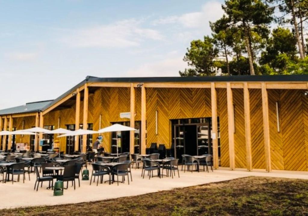 - un grand bâtiment en bois avec des tables et des chaises dans l'établissement MH 515 AMIRA TOUT CONFORT 3ch et 2sdb dans camping 4étoiles avec parc aquatique, à Saint-Julien-en-Born