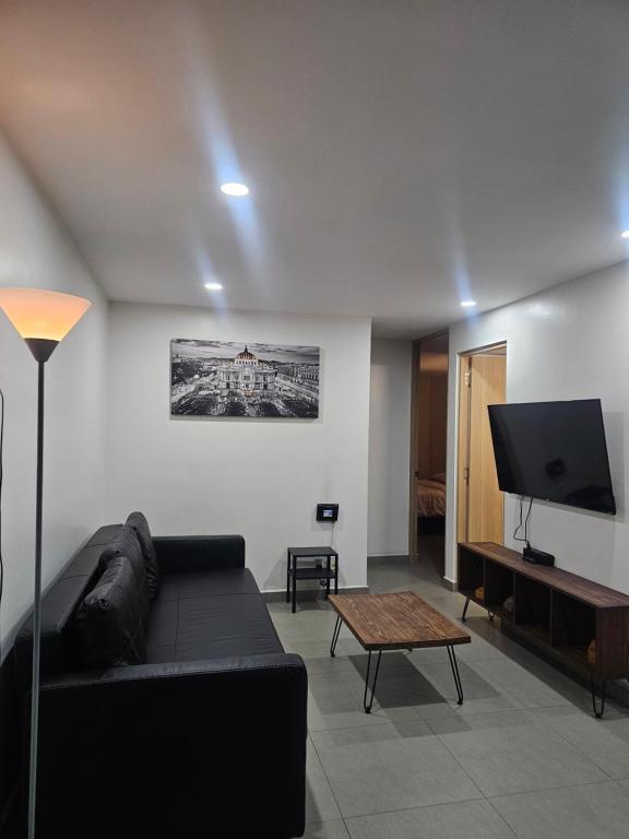 een woonkamer met een zwarte bank en een flatscreen-tv bij NSI Alameda Park Humboldt Mexico City in Mexico-Stad