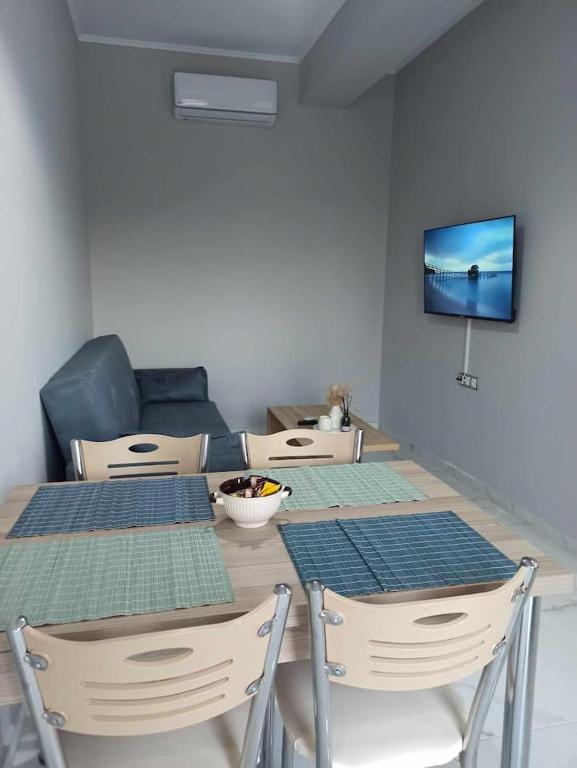a dining room table with four chairs and a television at Chios Cozy Apartment 1 in Sklaviá