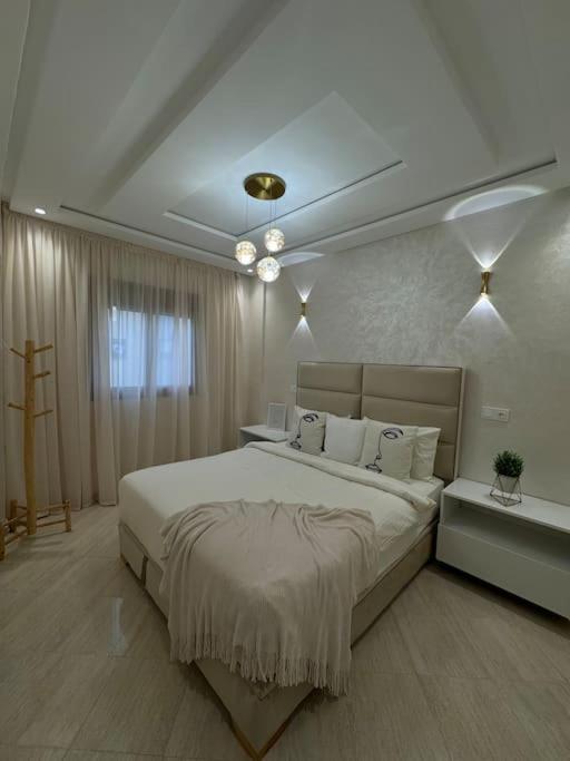 una camera da letto bianca con un letto grande e una finestra di Appartement Moderne a Meknès