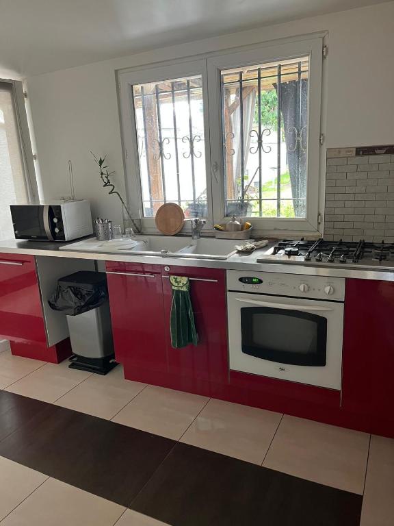 Il comprend une cuisine équipée d'une cuisinière rouge et blanche. four supérieur dans l'établissement Belle chambre à louer, à Argenteuil