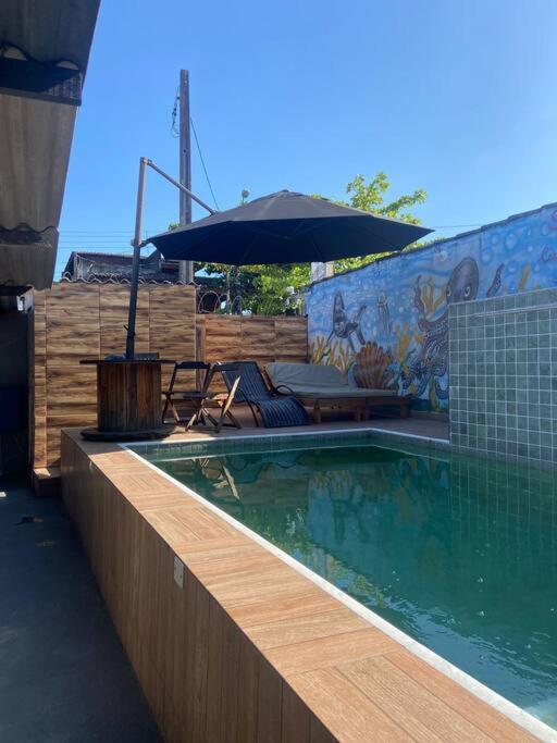 a swimming pool with an umbrella and a table at Casa com Piscina - Área da lazer familiar in Guarujá