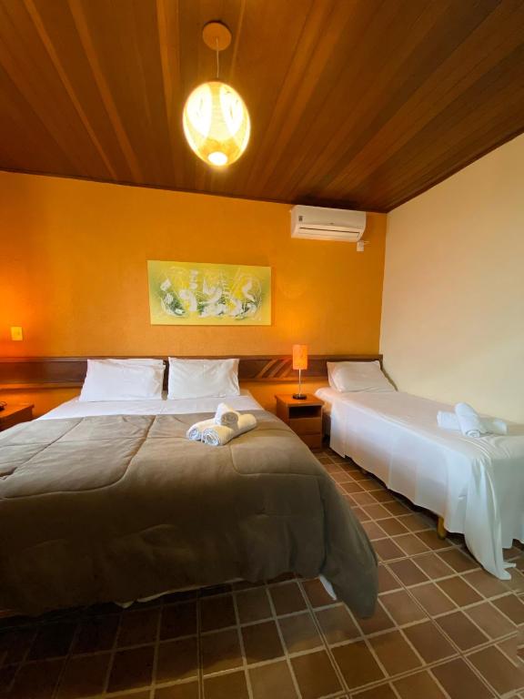 a hotel room with two beds and a lamp at Villa Zen Pirenópolis Conforto e Bem-Estar in Pirenópolis