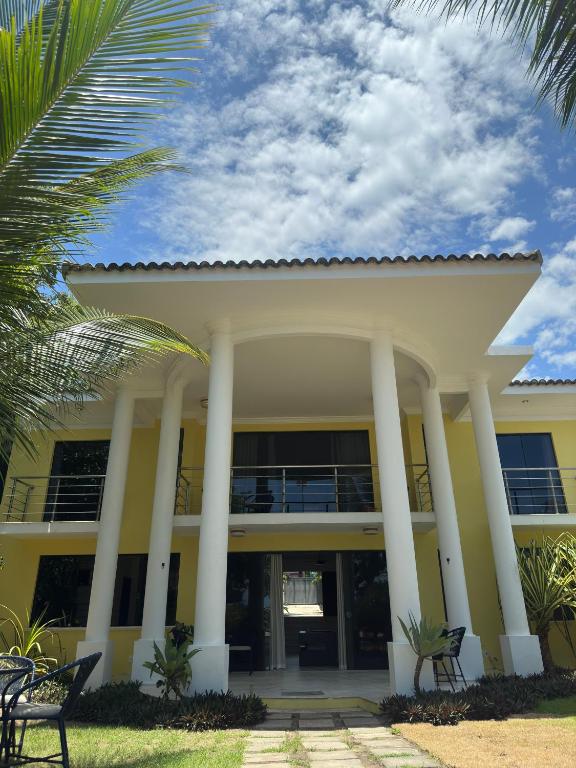 a large yellow building with white columns at Casa Mar Arraial d'Ajuda in Arraial d'Ajuda