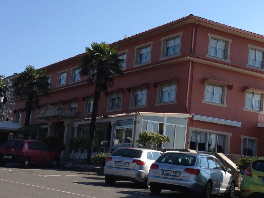 two cars parked in front of a red building at Hotel Garcas in Lavacolla