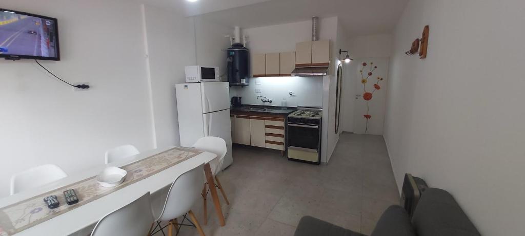 a small kitchen with a white refrigerator and a stove at Casa EL HORNERO 2 con cochera en gran Mendoza in Godoy Cruz