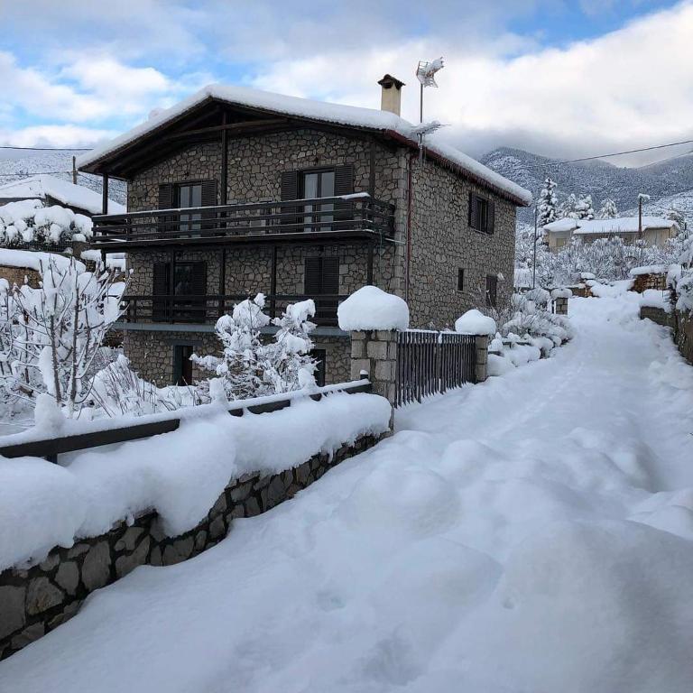a house covered in snow in front of a yard at Drymaia Chalet in Amfikleia