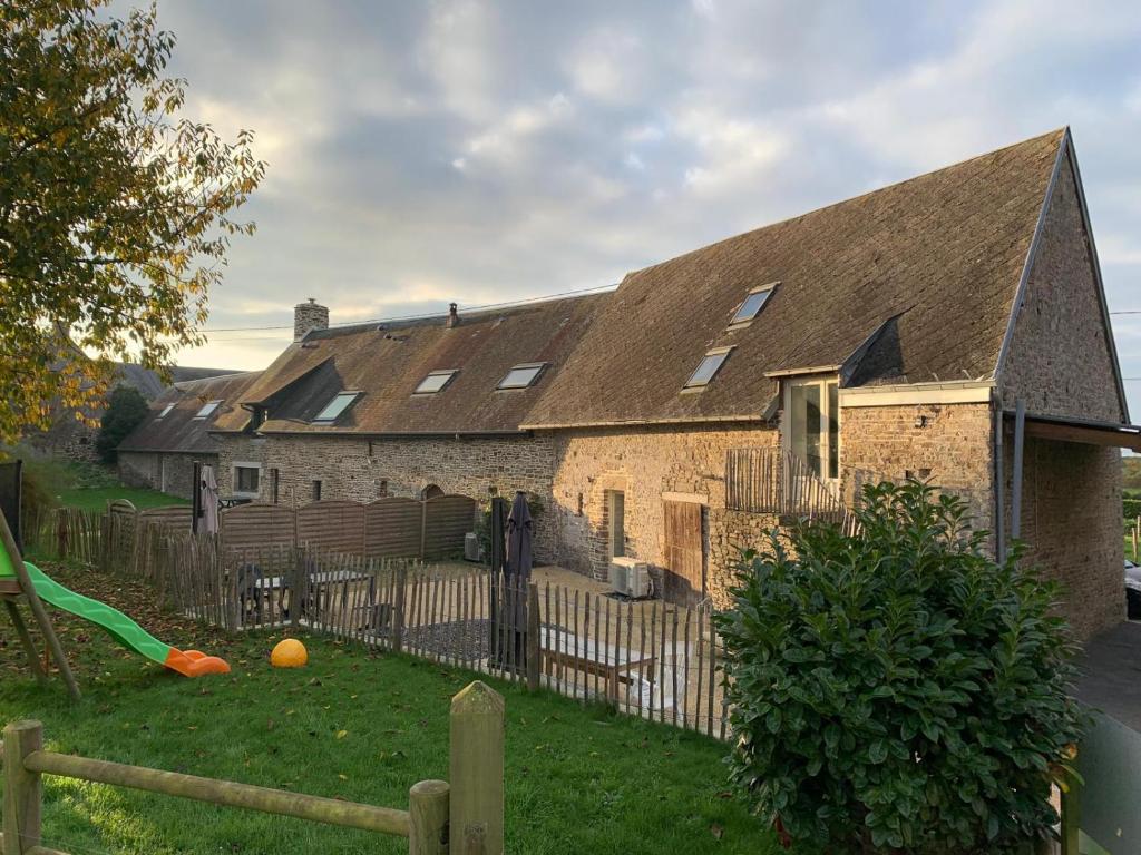 une maison en briques avec une clôture et un toboggan vert dans l'établissement La Grande Hogue, à Dragey-Ronthon