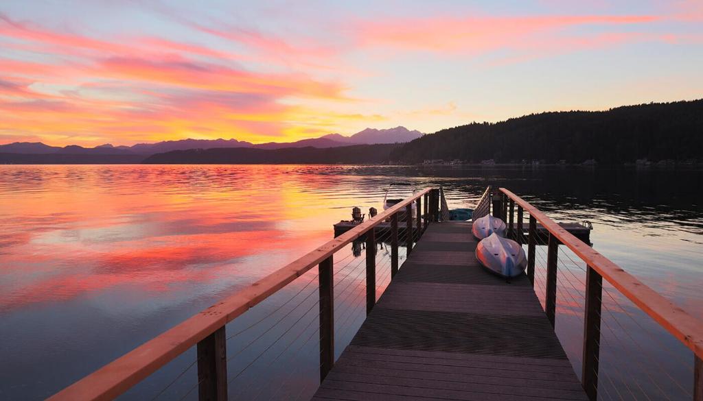 un molo con una barca sul lago al tramonto di Hood Canal Resort in Union, WA a Union
