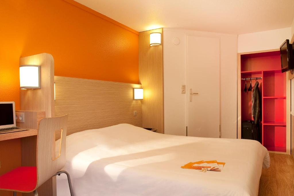 Cette chambre d'hôtel comprend un lit blanc et une chaise rouge. dans l'établissement Premiere Classe Valenciennes Ouest Petite Foret, à Petite-Forêt