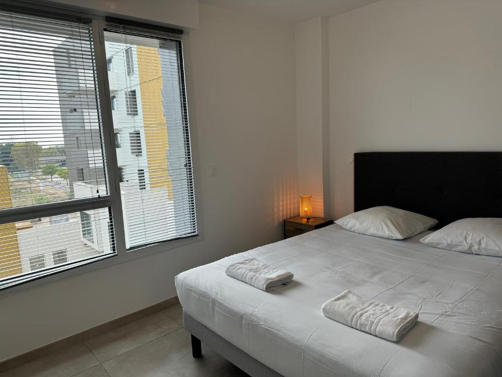 ein Schlafzimmer mit einem Bett und einem großen Fenster in der Unterkunft Colocation appartement terrasse XXL Port Marianne in Montpellier