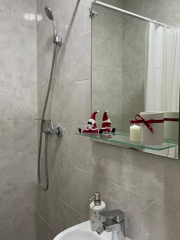 un bagno con doccia e decorazioni di Babbo Natale su una mensola di 'MONAS' mini apartments a Sombor