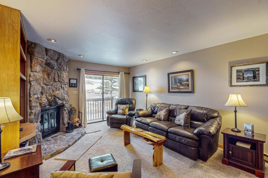 a living room with a leather couch and a fireplace at Whispering Pines in Durango Mountain Resort