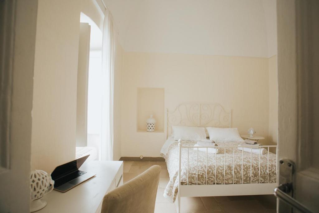a white bedroom with a bed and a table at Dimora Del Vicolo in Ostuni