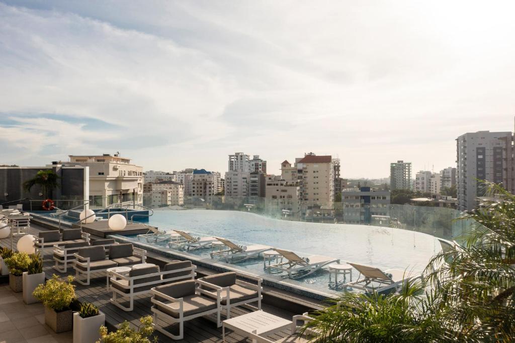 a swimming pool with lounge chairs on a building at Embassy Suites by Hilton Santo Domingo in Santo Domingo