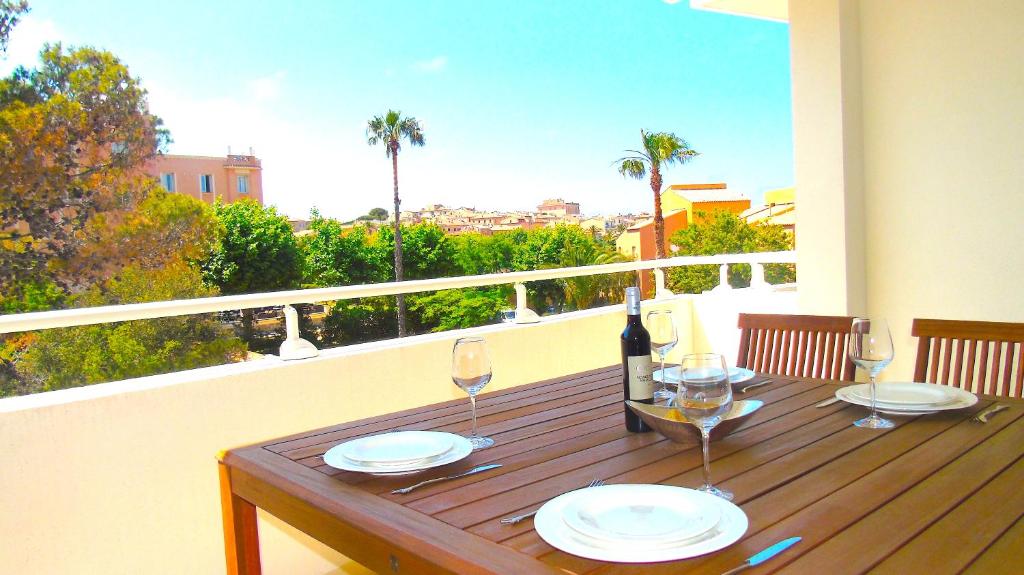 - une table en bois avec des verres de vin sur le balcon dans l'établissement Résidence Le Cosimo, à LʼÎle-Rousse