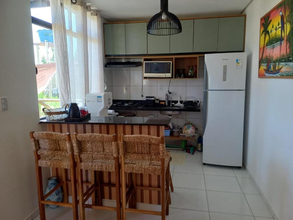 eine Küche mit einem weißen Kühlschrank und einigen Stühlen in der Unterkunft Chale Ville Maramar 401 in Luis Correia