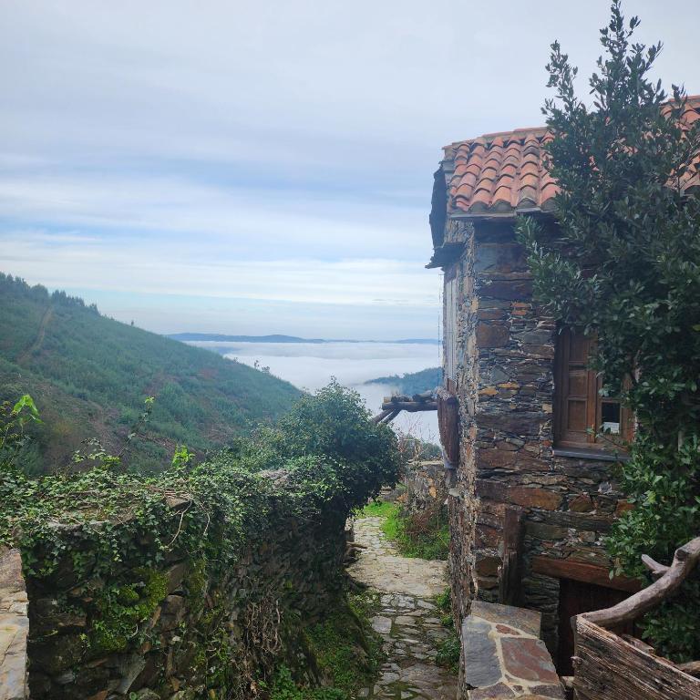uma casa de pedra numa colina com vista em Casa da Pedra em Talasnal