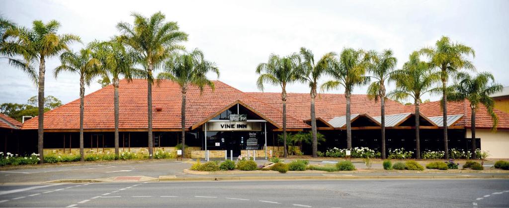 a building with a red roof with palm trees at Vine Inn Barossa in Nuriootpa