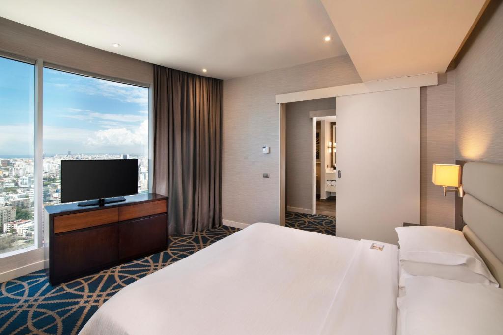 a hotel room with a bed and a flat screen tv at Embassy Suites by Hilton Santo Domingo in Santo Domingo