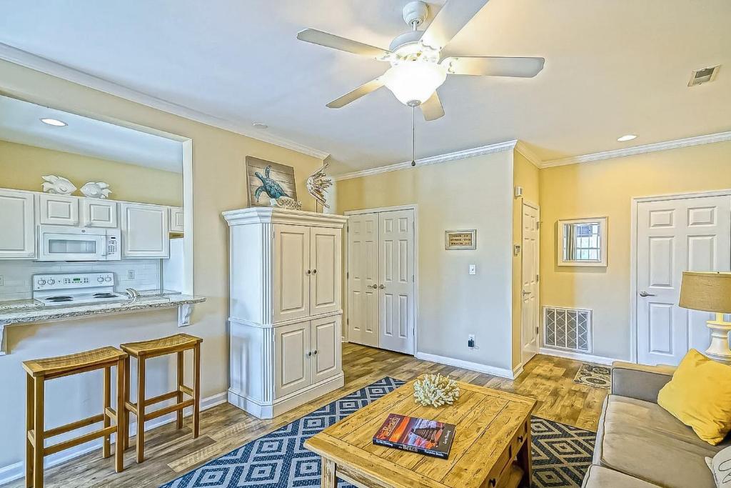 a living room with a ceiling fan and a table at Creekwood --- 1400 Pebble Dr #1410 in The Plantations