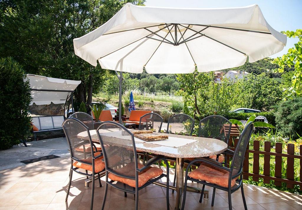 ein Tisch und Stühle mit einem Sonnenschirm auf einer Terrasse in der Unterkunft Apartment Mira in Supetarska Draga