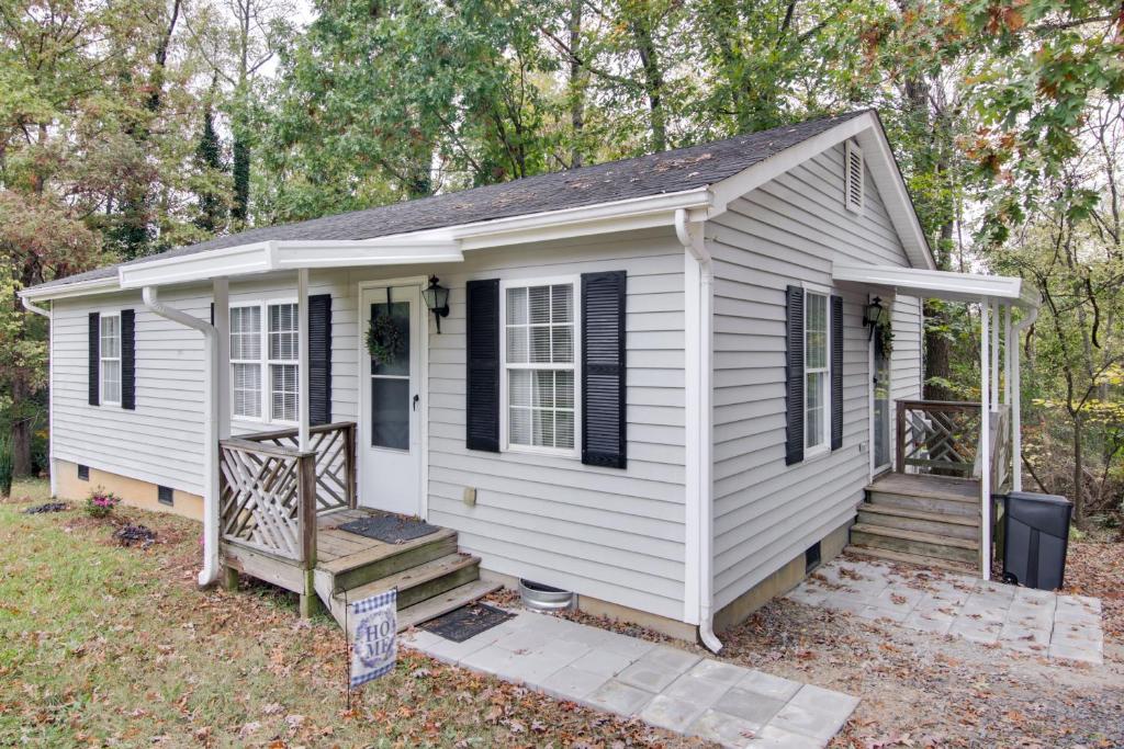 a small white house with a porch and stairs at Near Lake Wylie - Updated Cottage with Yard! in Rock Hill